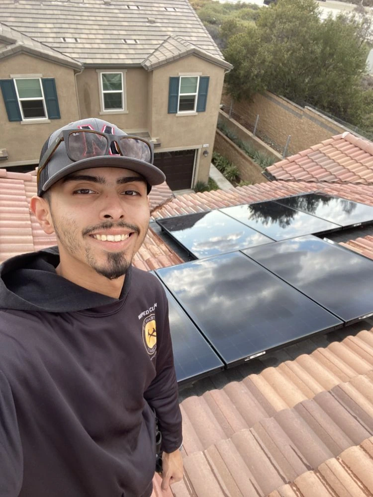 Christian Paiz beside freshly cleaned rooftop solar panels
